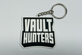 Two stickers on a metallic surface, one with a character design and the other with 'Vault Hunters' text.